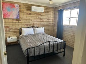 a bedroom with a bed and a brick wall at Starlight Motor Inn in Roma +37 photos