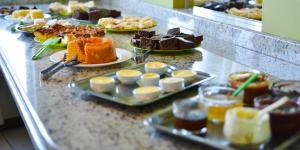 una línea de buffet con diferentes tipos de pasteles y postres en Hoteis Cattoni Executive, en Lages