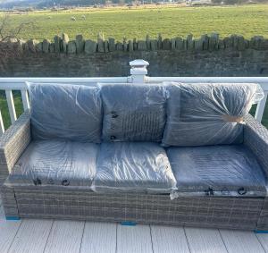 a couch covered in plastic sitting on a porch at 3 bedroom, 2 bathroom caravan Presthaven Beach Resort in Talacre