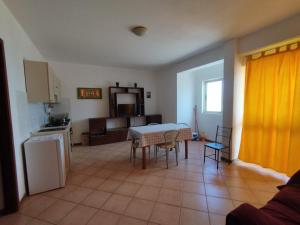 a living room with a table and a kitchen with a yellow curtain at Ca Gabbiano 6 in Santa Maria