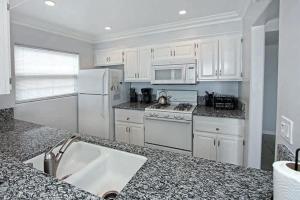a kitchen with white appliances and a granite counter top at 8-Bedroom Beachfront Triplex – Ideal for Extended apts in Newport Beach