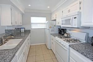 a kitchen with white cabinets and a stove top oven at 8-Bedroom Beachfront Triplex – Ideal for Extended apts in Newport Beach