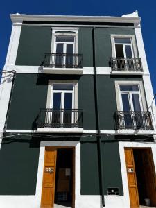 a green and white building with windows and doors at Sailor Setubal in Setúbal