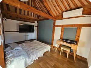 a bedroom with a bed and a desk with a television at 경상북도 감성숙소 청화소담 in Yeongcheon