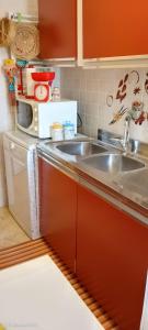 a kitchen with a sink and a microwave at Casa con veranda a 10 min dal mare in Lizzano