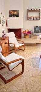 a living room with two chairs and a tv at Casa con veranda a 10 min dal mare in Lizzano