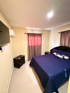 a bedroom with a purple bed and a red curtain at Comforthub Apartment in Higuey