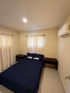 a bedroom with a large blue bed with two tables at Comforthub Apartment in Higuey