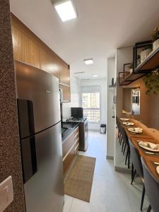 a kitchen with a stainless steel refrigerator and a long table at Infinity 1302 - Piscina, Academia e Praia a Poucos Passos in Vila Velha