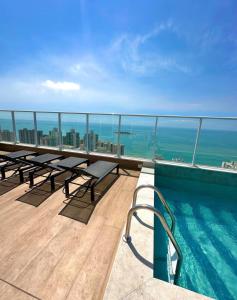 a balcony with tables and a swimming pool on a building at Infinity 1302 - Piscina, Academia e Praia a Poucos Passos in Vila Velha