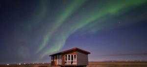 a building with the aurora in the sky at Vestra-Fíflholt cabin 1 in Hvolsvöllur