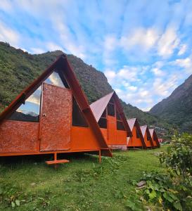 a row of tents in a field with mountains at Salkantay Star Camp Chaullay in Colcapampa