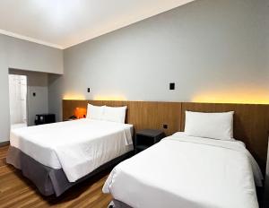 two beds in a hotel room with white sheets at Hotel Del Rey by Poty - RUA XV DE NOVEMBRO in Curitiba