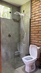 a bathroom with a toilet and a glass shower at Estância da Mata in CÃ¡ssia +36 photos