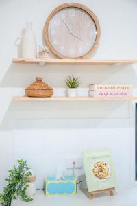 a clock and a plate on a shelf with plants at The Shell Shack on Whisper Bay in Cannonvale