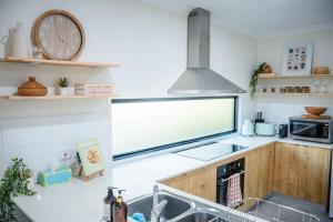 a kitchen with a sink and a clock on the wall at The Shell Shack on Whisper Bay in Cannonvale +20 photos
