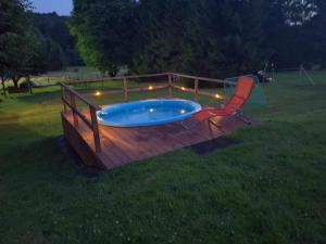 a deck with a hot tub and a chair at Domki Całoroczne Pod Lasem in Łobozew