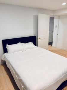 a bedroom with a large white bed with a black headboard at Just Peace Homes in Moncton