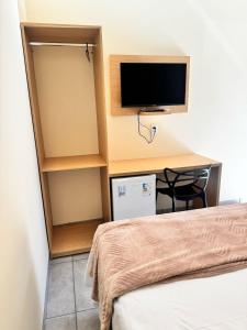 a room with a bed and a desk with a television at Hotel Miranda Maracaju in Maracaju