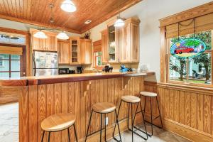 a kitchen with wooden cabinets and a bar with stools at IC2 - Endless Summer Cottage in Manteo