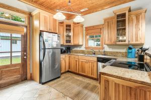 a kitchen with wooden cabinets and a stainless steel refrigerator at IC2 - Endless Summer Cottage in Manteo +23 photos