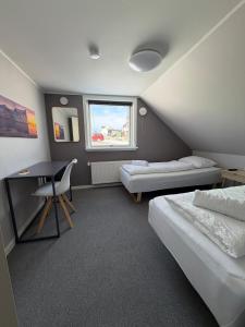 a room with two beds and a desk and a window at Møller Guesthouse in Ilulissat