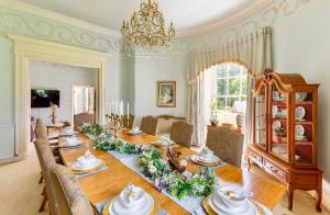 a dining room with a long table with flowers on it at Unique Manor House PLUS Jacuzzi PLUS BBQ Cabin in Maybole