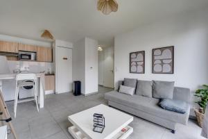 a living room with a couch and a kitchen at Ô Bon Vivre - Vidéo-projecteur, Wifi, Netflix inclut, Terrasse in Toulouse