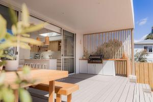 a balcony with a wooden table and a kitchen at Bay Days - Binalong Bay in Binalong Bay