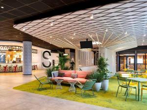 a lobby with a couch and tables and chairs at ibis Paris CDG Airport in Roissy-en-France