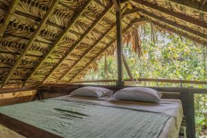 a bed in a wooden structure with two pillows at El Vijo Surf in Nuquí +78 photos