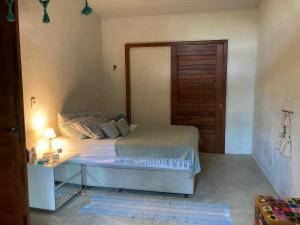 a bedroom with a bed and a table and a door at Casa Filtro Morere in Cairu