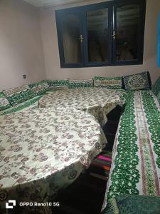 a bedroom with two beds with green and white sheets at Gite souran in Imlil