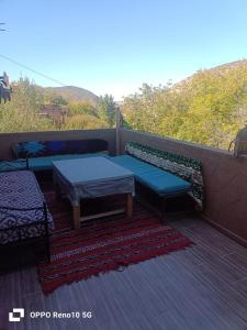 a patio with two benches and a table and a rug at Gite souran in Imlil
