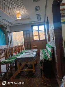 a dining room with a table and chairs and windows at Gite souran in Imlil
