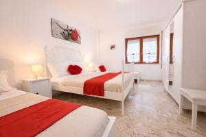 a white bedroom with two beds and a window at Casa Sant'Antonio in Bari