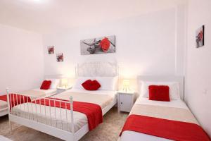 two beds in a white room with red pillows at Casa Sant'Antonio in Bari