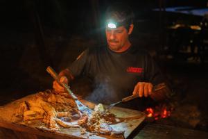 a man is cooking food on a grill at El Vijo Surf in Nuquí