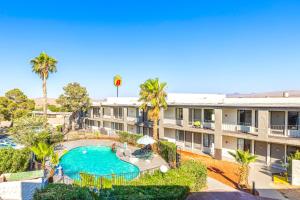 an apartment building with a swimming pool and palm trees at Super 8 by Wyndham Barstow in Barstow