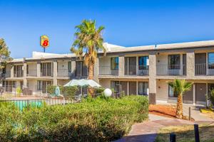 an apartment building with a pool and palm trees at Super 8 by Wyndham Barstow in Barstow