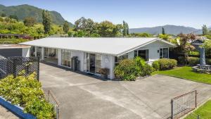 an aerial view of a white house with a driveway at The Bach - Pohara in Pohara