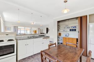 a kitchen with white cabinets and a wooden table at The Bach - Pohara in Pohara