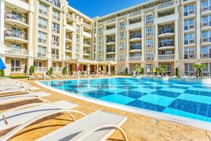 an outdoor swimming pool with chaise lounge chairs in front of a building at Rena Hotel - All Inclusive in Sunny Beach