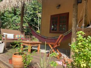 a hammock and a table and chairs in a garden at Casa Filtro Morere in Cairu +2 photos