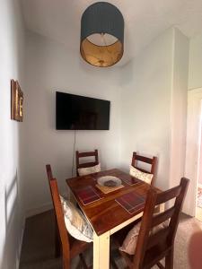 a dining room table with chairs and a flat screen tv at Castle Brae Apartment in Stirling