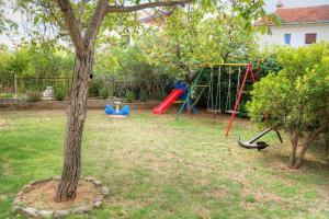 a yard with a playground with a tree and swings at Apartment Crikvenica 19 in Crikvenica