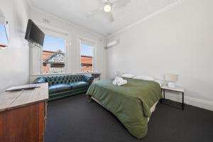 a bedroom with a bed and a couch and a tv at The Oriental Hotel in Newcastle