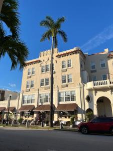 a building with a palm tree in front of a street at The Green Room - Pool View with Parking Spot at 1920s Historic Residence with 24x7 Reception Desk on Palm Beach Island in Palm Beach