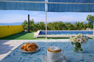 a table with croissants and a cup of coffee at Villa Andy -private yard, swimming pool, panoramic view in Imotski