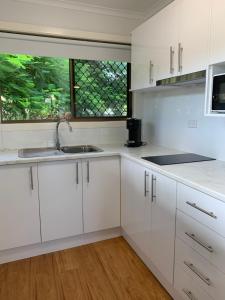a kitchen with white cabinets and a sink and a window at Hidden Gem at The Bay - Resort Pool - 300m to Beach in Urangan